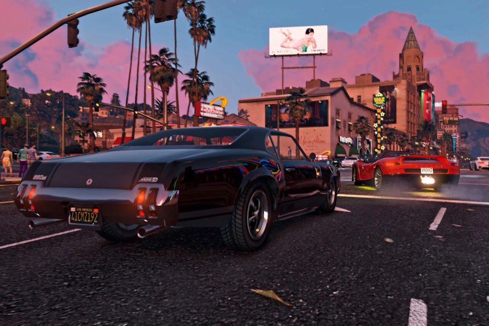 Cars on Vinewood Boulevard at dusk, with palm trees and neon signs